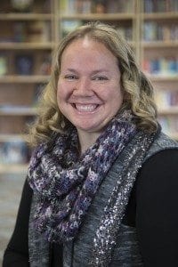 A woman wearing a scarf and smiling for the camera.