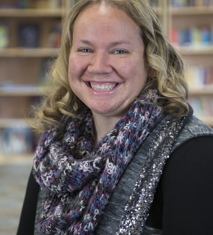 A woman wearing a scarf and smiling for the camera.