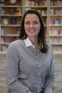 A woman standing in front of bookshelves.